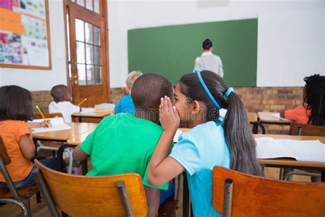 Cute Pupils Whispering In Classroom Stock Photo - Image: 43658668