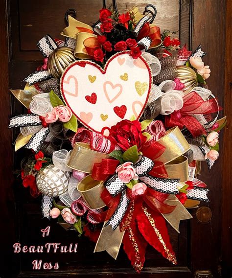 a heart shaped wreath is hanging on a door with ribbons and bows around ...