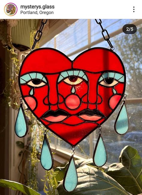 a stained glass heart hanging from a window with teary eyes and tears on it