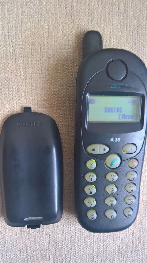 two old cell phones sitting on the floor next to each other, one is black