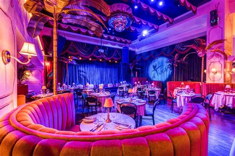 the interior of a fancy restaurant with purple and red lighting, tables ...