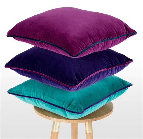 four pillows stacked on top of each other in different colors and sizes sitting on a stool