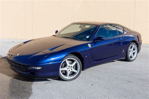 a blue and brown sports car parked in front of a building with a tan wall