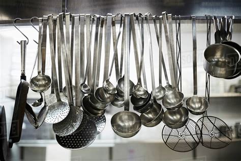 Utensils on metal rack in commercial kitchen - Stock Photo - Dissolve