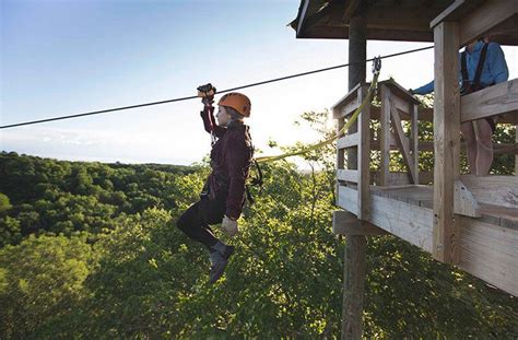 A young woman rides a zipline above a forest | Adventure park ...