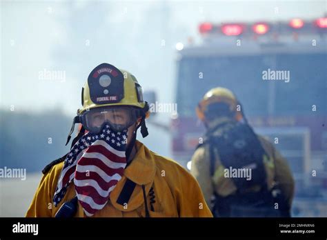 A firefighter covers his face with a U.S. flag scarf as he fights the Easy Fire, Wednesday, Oct ...