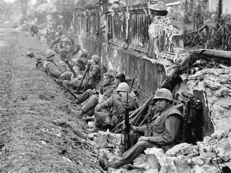 A unit of the 1st Battalion, 5th Marine Regiment, rests alongside a ...