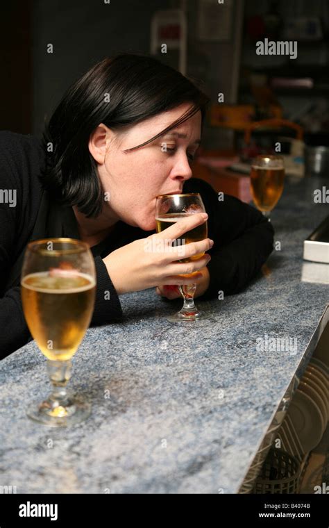 Very drunk female sitting at a bar drinking beer and already very worse for wear Stock Photo - Alamy