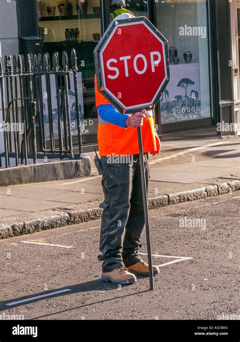 Road Worker standing in road holding Stop sign, London Stock Photo - Alamy