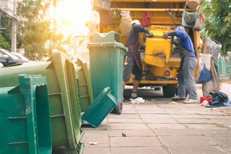 Garbage collector on the garbage truck.Sweeper or Worker are loading waste into the garbage ...