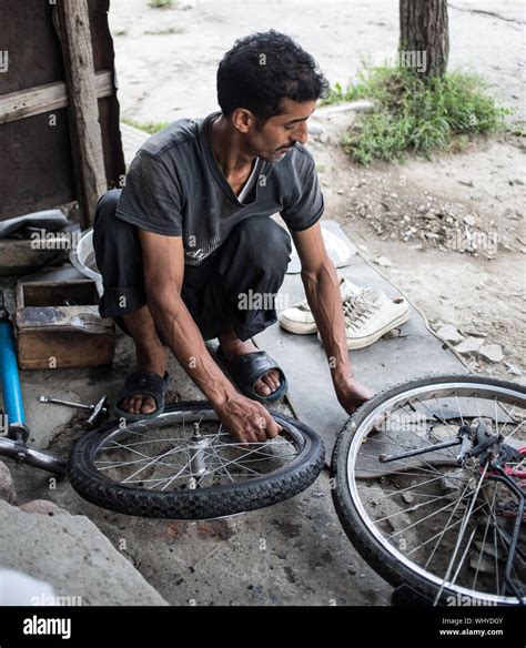 A bicycle repair man fixing a flat tire on a bike on a late afternoon ...