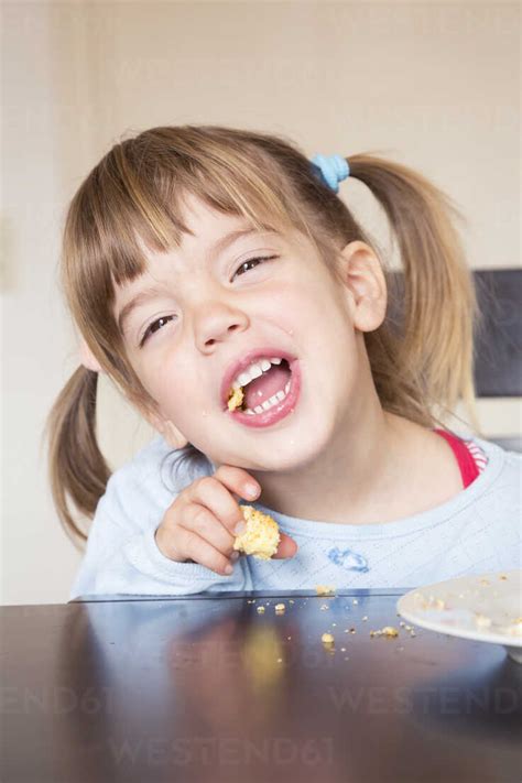 Portrait of little girl eating cake with open mouth stock photo