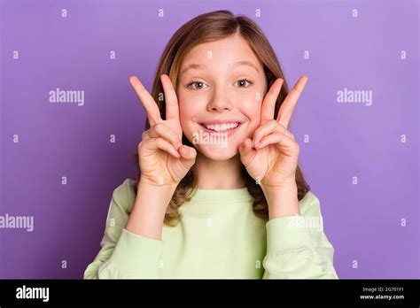 Photo of young attractive school girl happy positive smile show peace v-sign funny isolated over ...