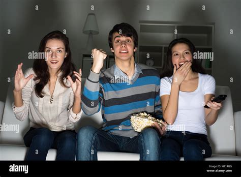 group of young people watching TV on the couch Stock Photo - Alamy