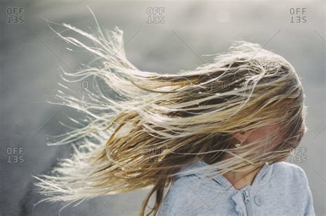 A blonde girl's hair blowing in the wind, obscuring her face stock ...