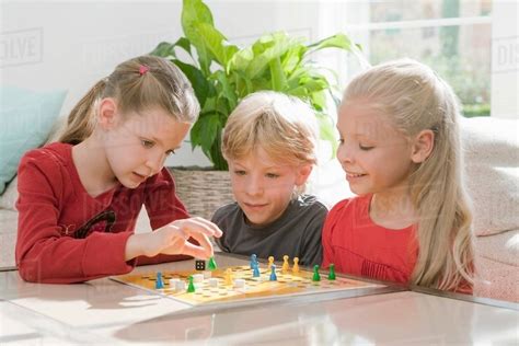 Three children playing a board game - Stock Photo - Dissolve