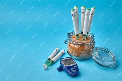 Premium Photo | Insulin syringe pens stuck in a jar of brown cane sugar and a glucose meter on a ...