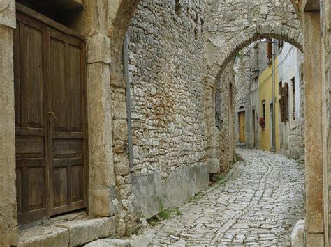 an alley way with cobblestone stone buildings and arched doorways on ...