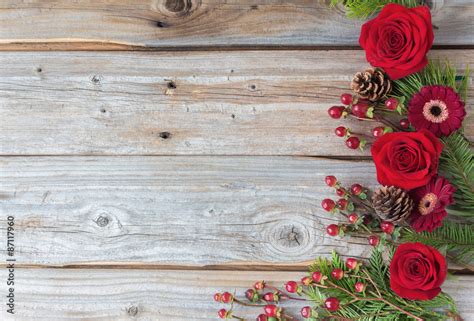 horizontal image of a group of bold red roses and cranberries placed on one side of the image on ...