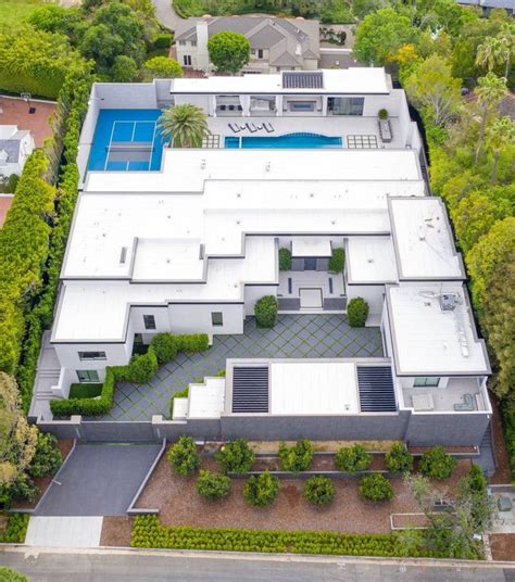 an aerial view of a house with a pool and tennis court in the foreground