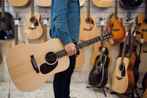 Young Man Holding Acoustic Guitar in Music Store Stock Photo - Image of ...