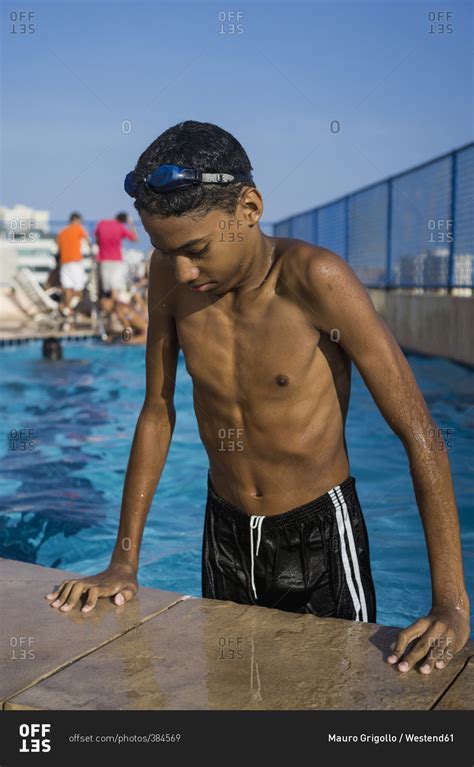 Teenage boy getting out of swimming pool stock photo - OFFSET