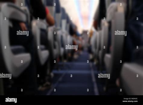 passenger sit on seat in airplane. aisle in aeroplane interior. blurry ...