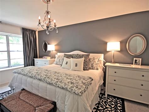 Rich light from lamps and a chandelier emanates throughout this romantic white and gray bedroom ...