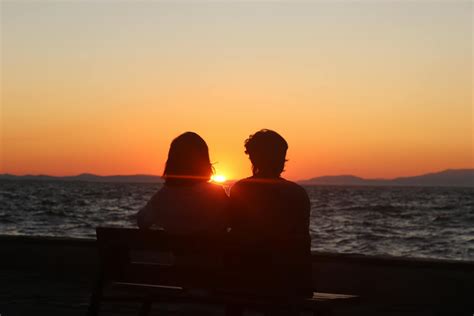 Silhouette of a Couple Sitting on Bench in Front of the Sea during Sunset · Free Stock Photo