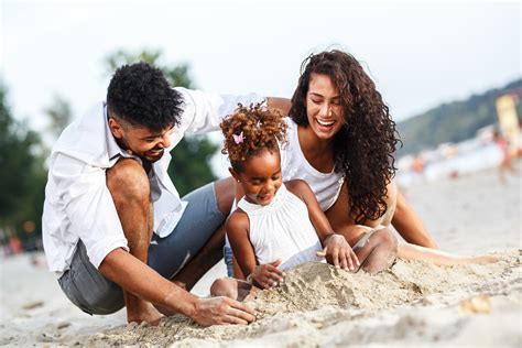 Young mixed race family sitting and relaxing at the beach on beautiful ...