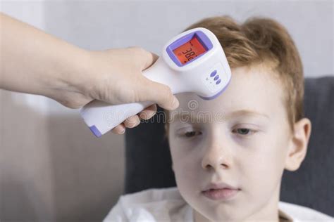 The Hand Uses a Modern Electronic Infrared Thermometer, the Boy& X27;s Body Temperature is ...