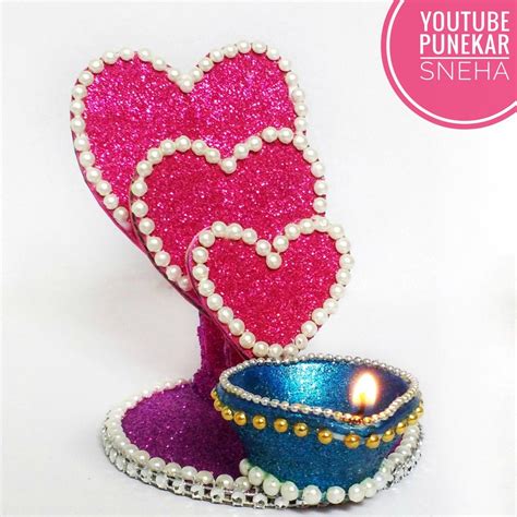 a small blue bowl with a lit candle in it next to a pink heart shaped box