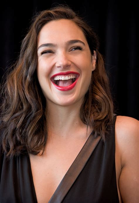 a woman smiling and wearing a black dress with red lipstick on her lips in front of a black ...