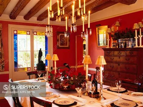 Lighted candelabra above table set for lunch in pink cottage dining room - SuperStock