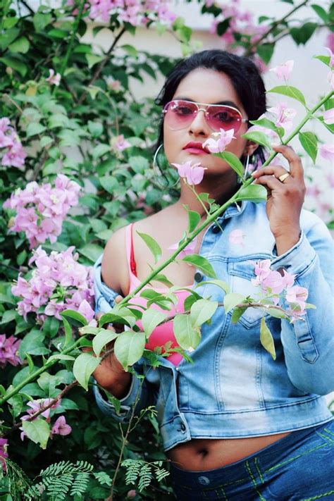 a woman wearing sunglasses and denim jacket standing in front of pink ...