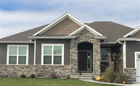 a gray house with white trim and two garage doors on the front door is ...