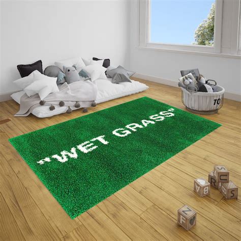 a green rug with the words wet grass on it in front of pillows and toys