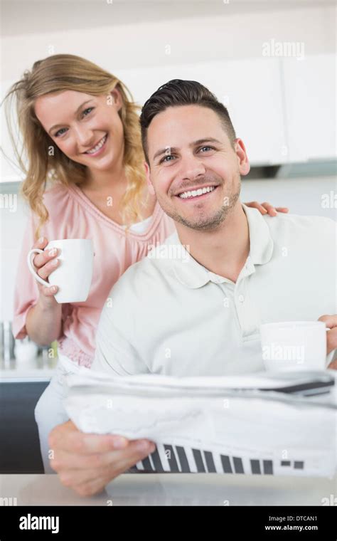 Couple with coffee mugs and newspaper in kitchen Stock Photo - Alamy