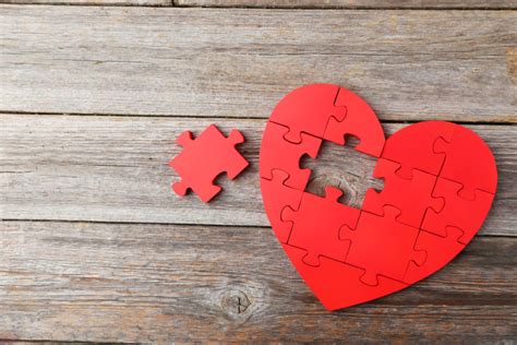 Red puzzle heart on grey wooden background - UVM Bored