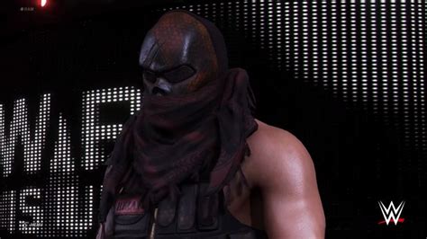 a man wearing a mask and scarf standing in front of a screen with the words wwe on it