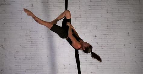 Woman acrobat practicing acrobatic stunts in the air while hanging ...