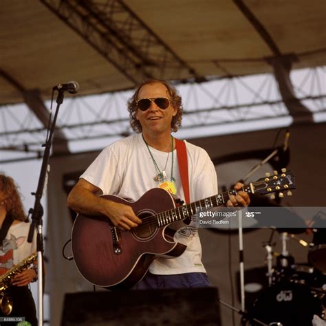 a man with sunglasses playing an acoustic guitar on stage