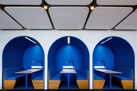 three blue benches in front of two white tables with one light on top ...