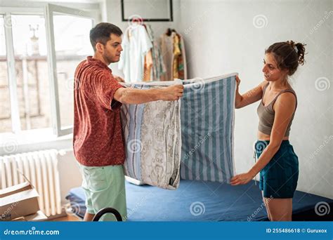 Cheerful Millennial Couple Making Bedsheet Together Stock Photo - Image ...