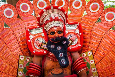 an elaborately decorated person with large feathers on his head and chest, standing in front of ...