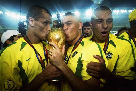 two soccer players kissing the world cup trophy