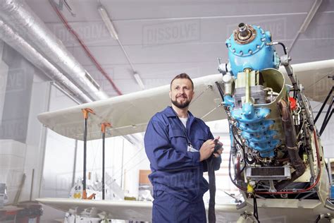 Portrait confident male airplane mechanic working on biplane in hangar - Stock Photo - Dissolve