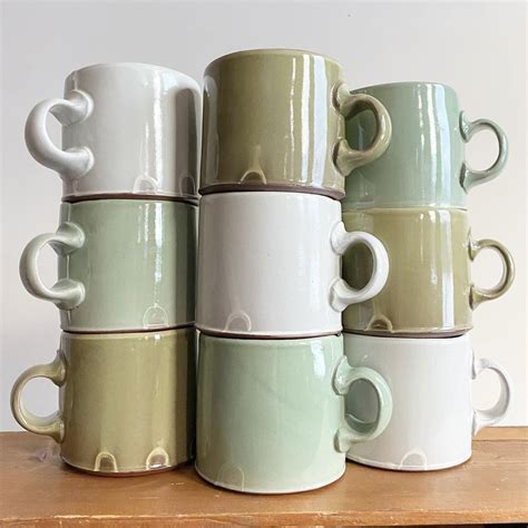 five coffee mugs stacked on top of each other in different shapes and sizes, sitting on a wooden ...
