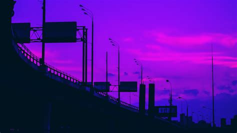 the sky is purple and pink with some clouds in it, as well as street lights