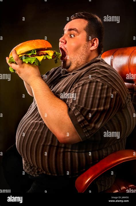 Fat man eating fast food hamberger. Breakfast for overweight person ...